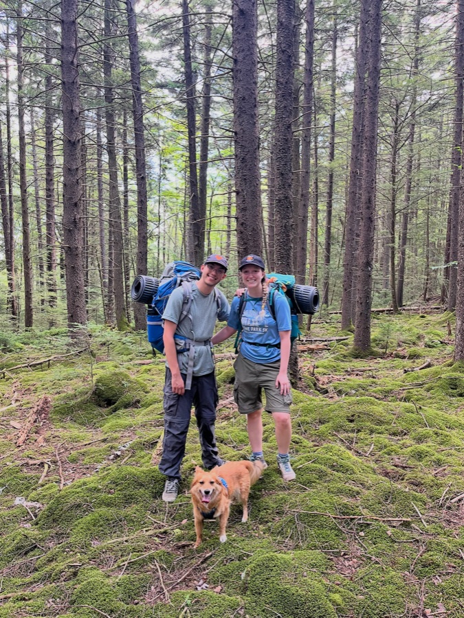 Mo Van de Sompel hiking with a companion and dog in a mossy forest